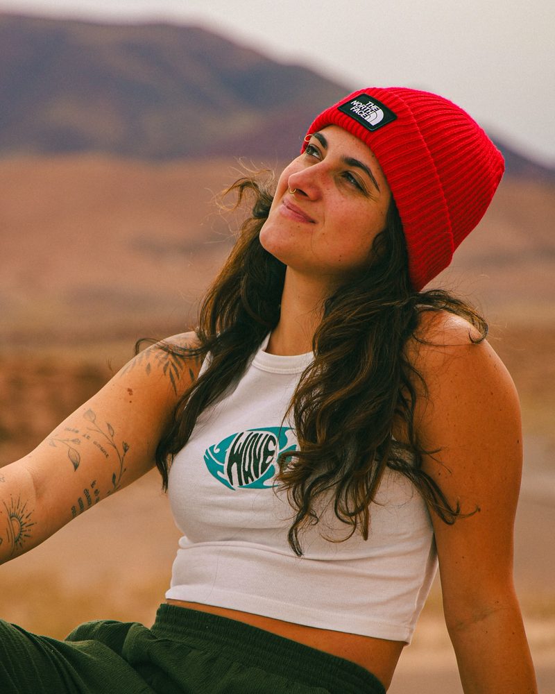 Carol Cirillo, cofundadora de Pindó, sentada al aire libre con un gorro rojo