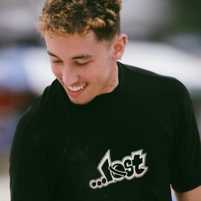Otávio Minelli, filmmaker y diseñador, sonriendo con camiseta negra